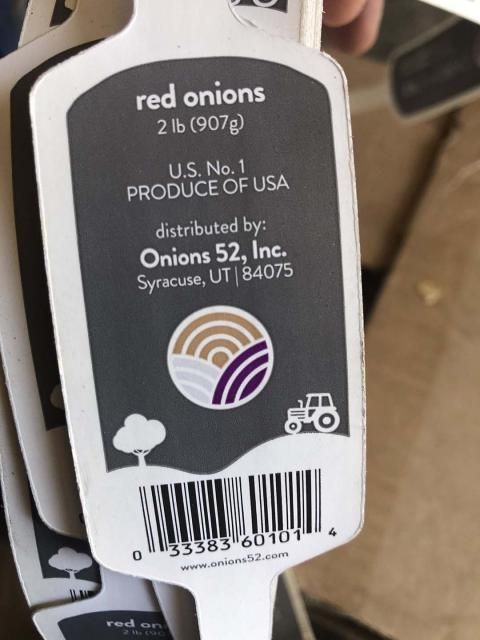 A person is holding a package of red onions