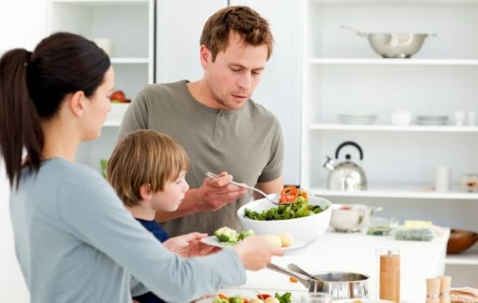 A family is eating a salad together in a kitchen.