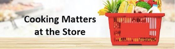 A red shopping basket filled with groceries is sitting on a wooden table.