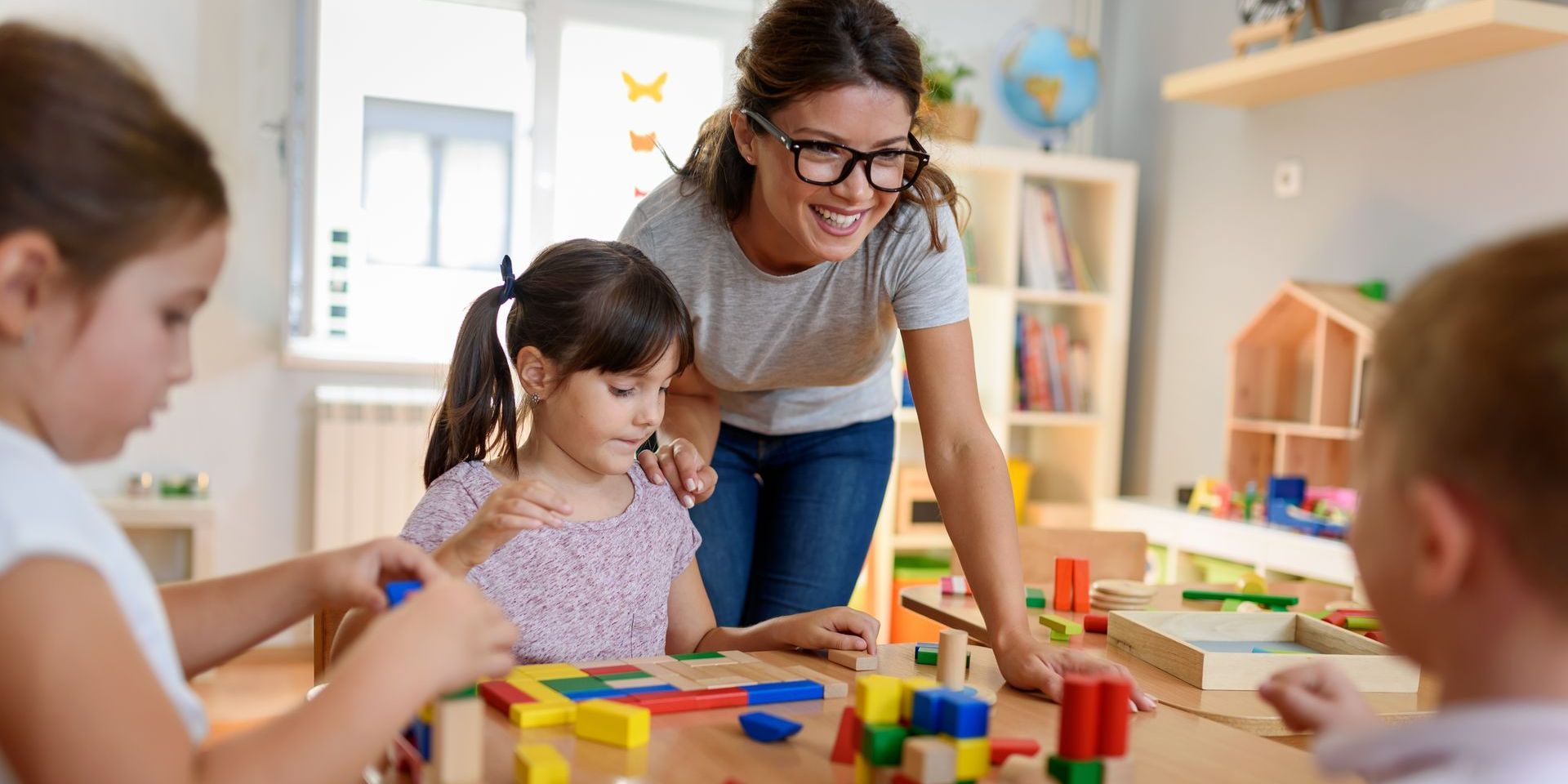 A woman is teaching a group of children how to play with blocks.