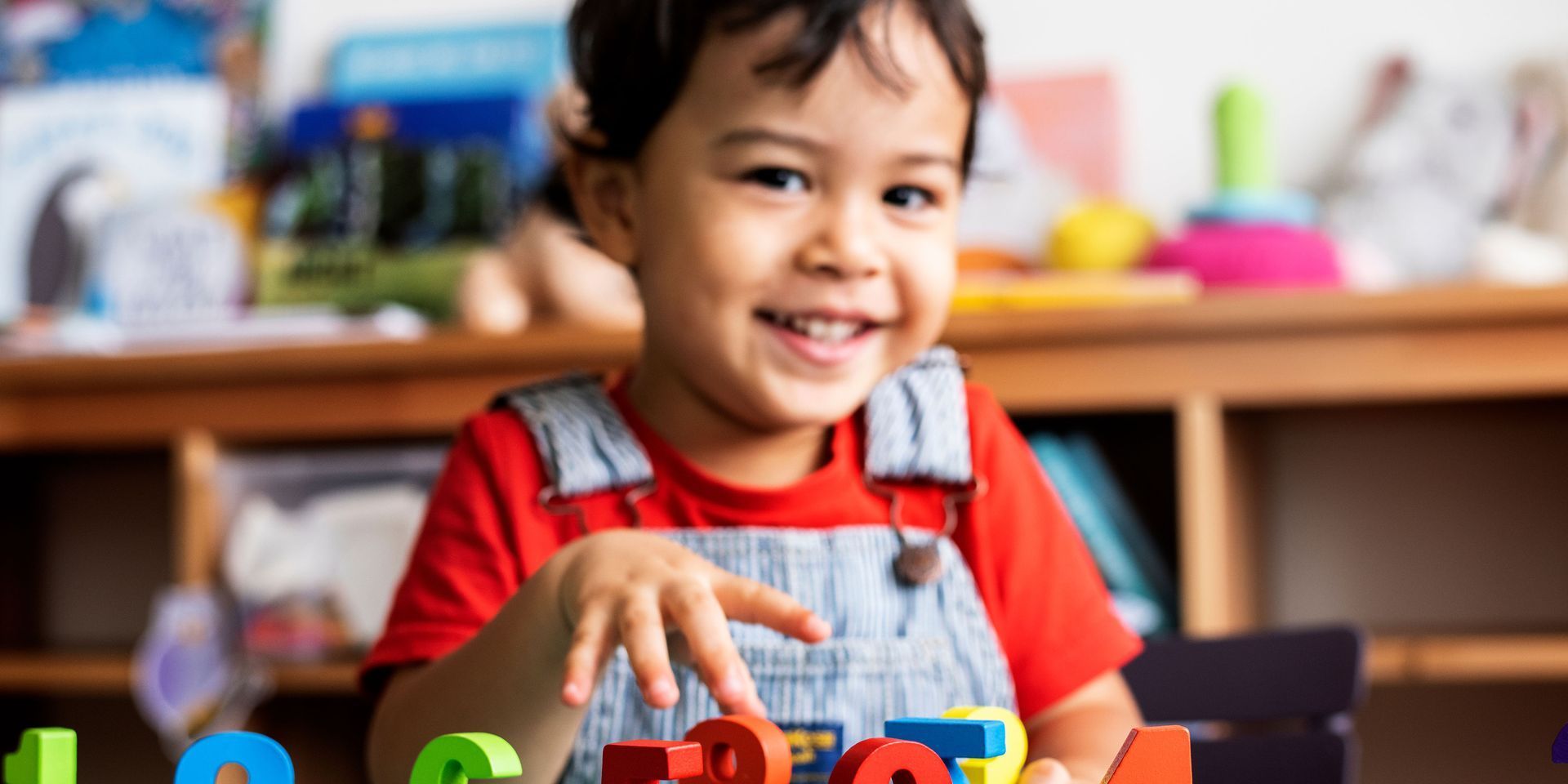 A young boy is playing with letters and numbers in a classroom.