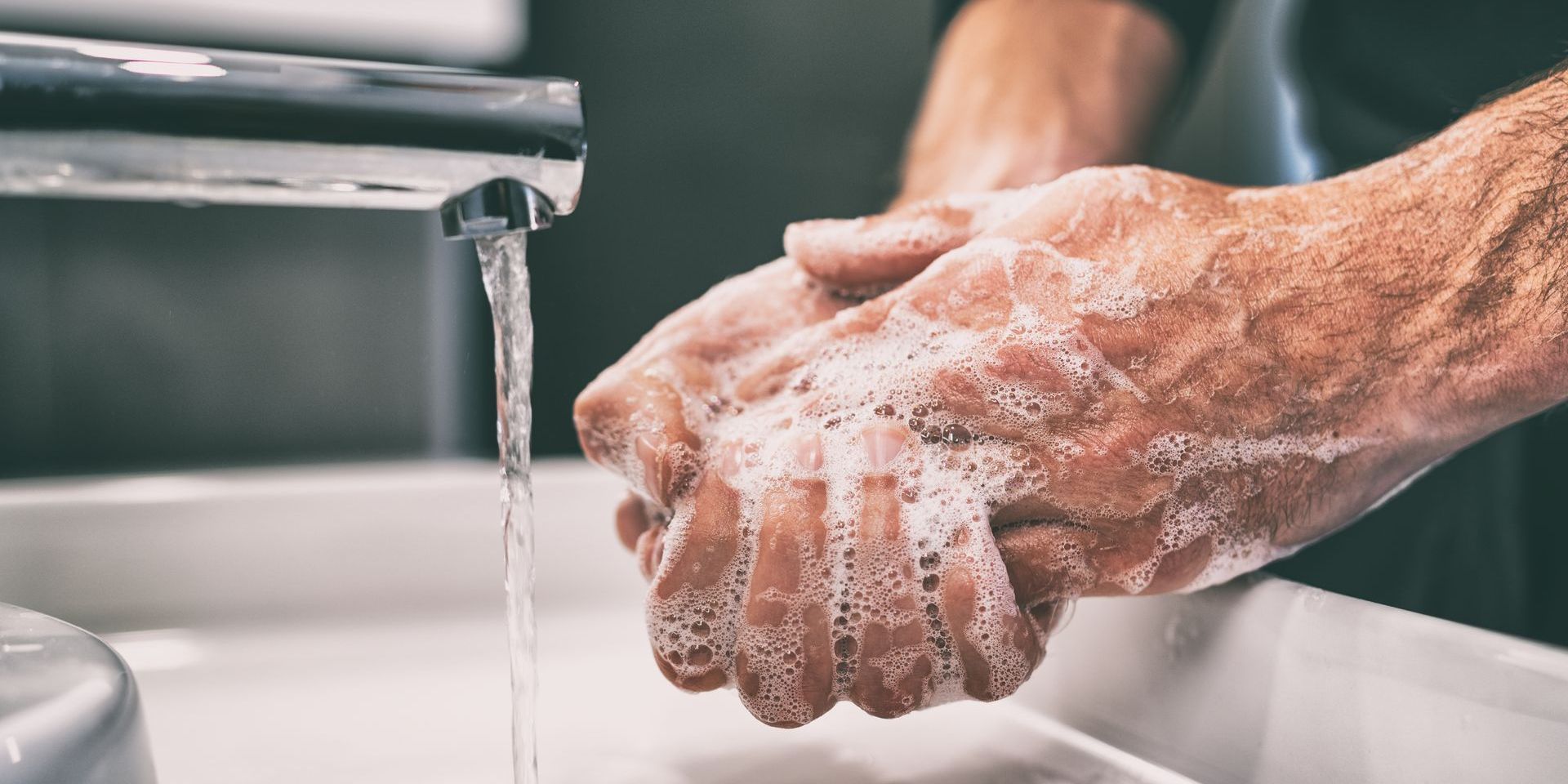 A man is washing his hands in a bathroom sink.