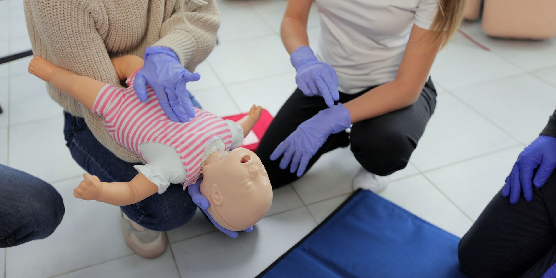 A group of people are kneeling down next to a baby doll.