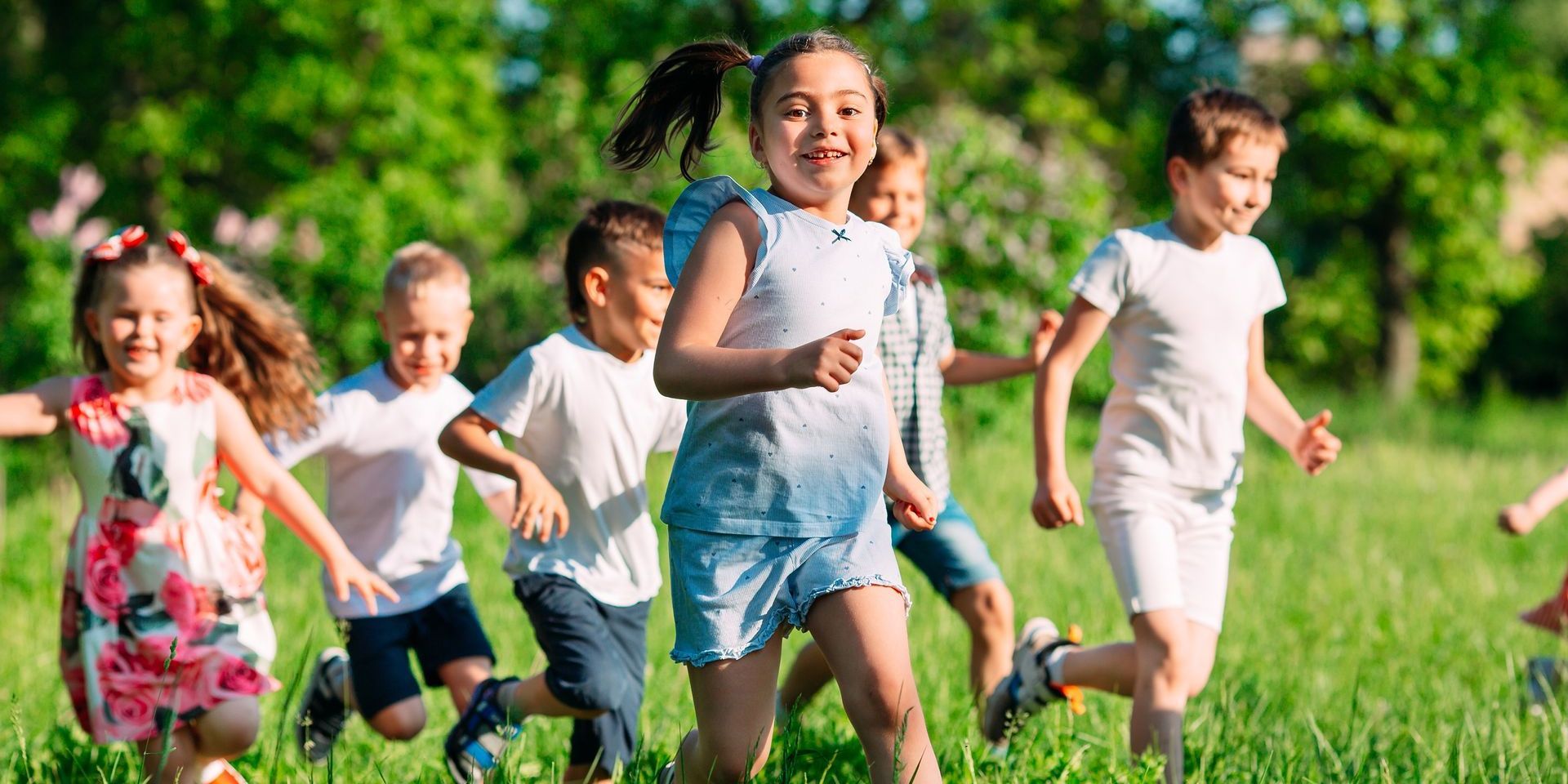 A group of children are running through a grassy field.