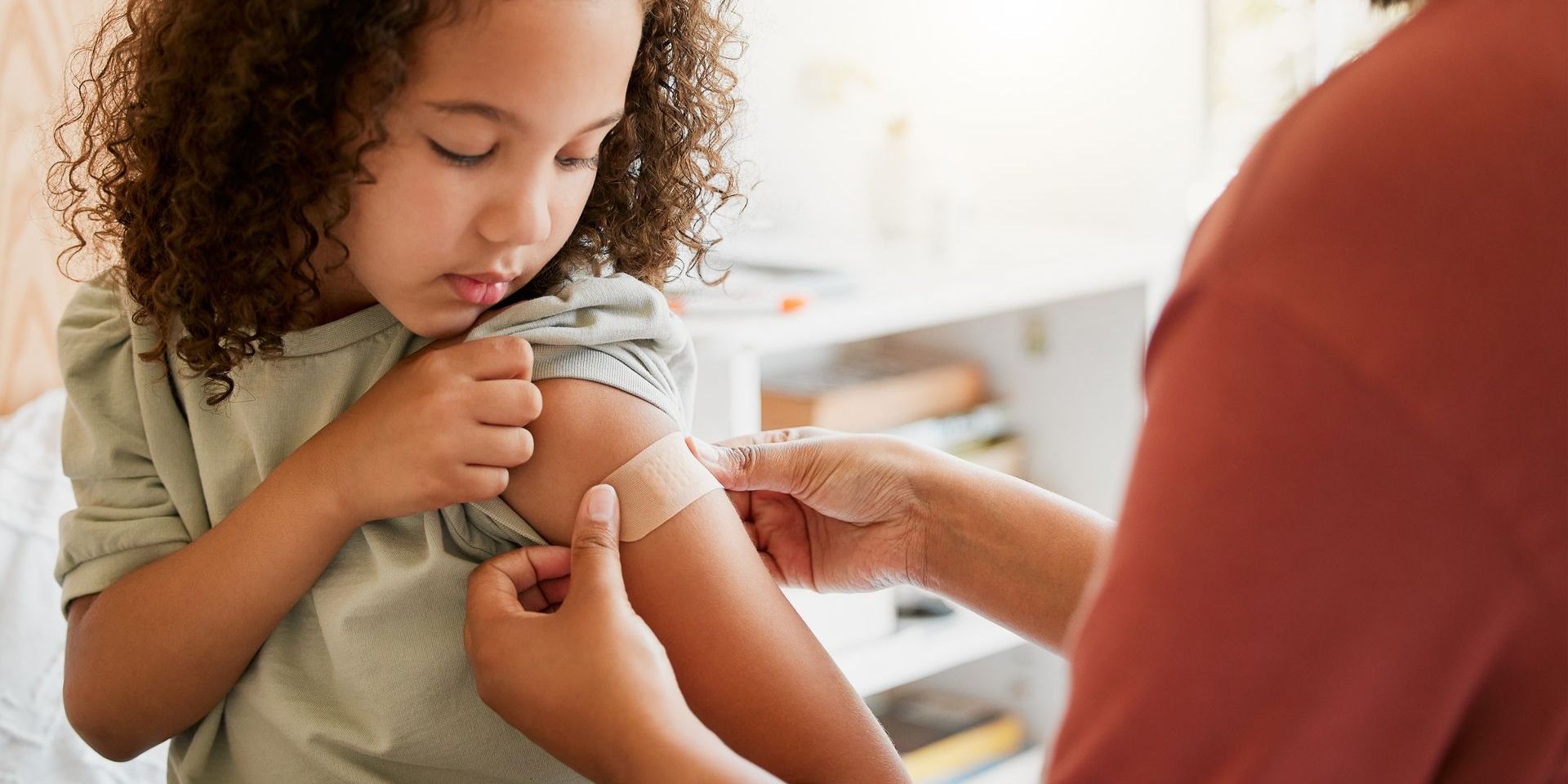 A little girl is getting a bandage on her arm.