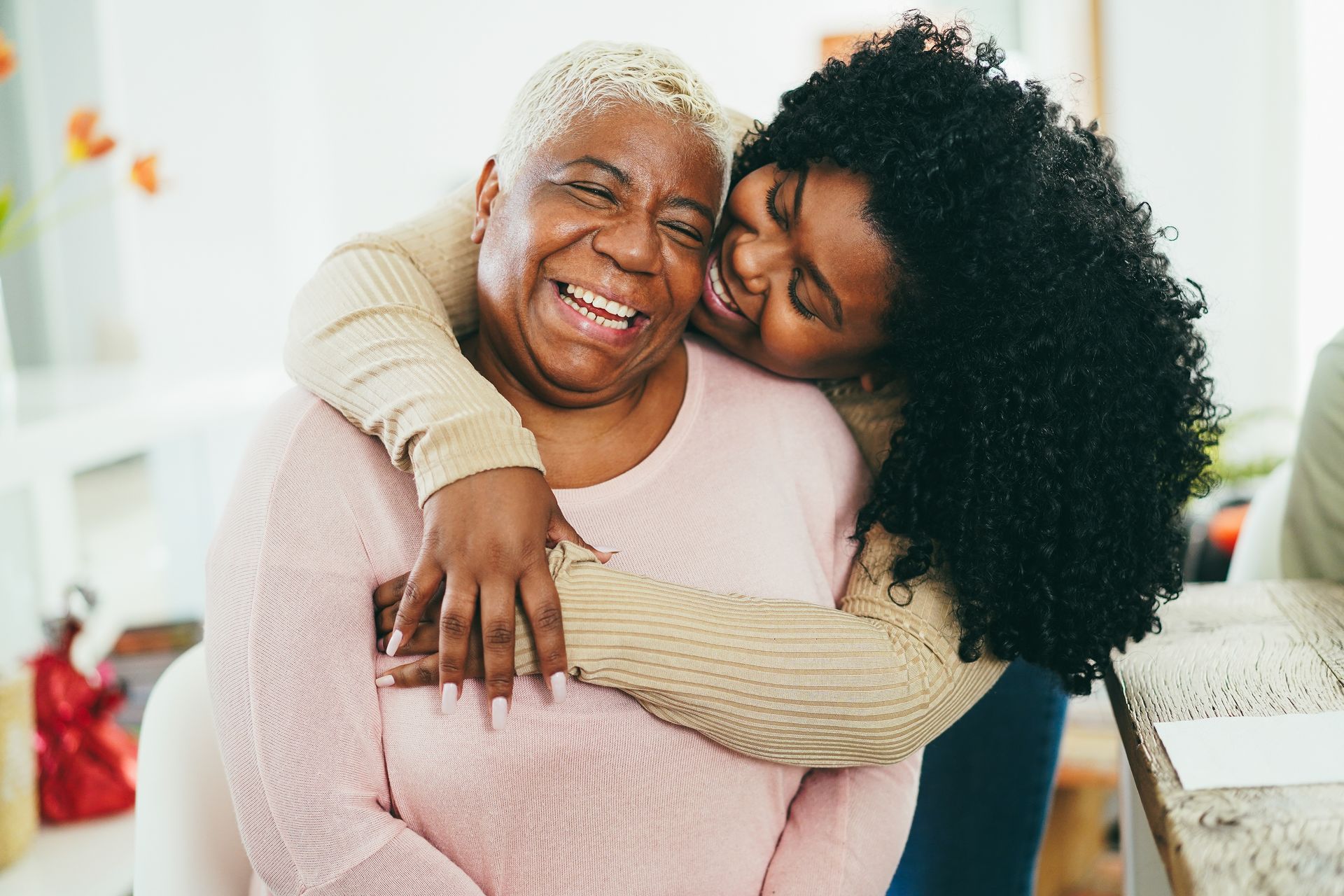 A young woman is hugging an older woman in a living room.