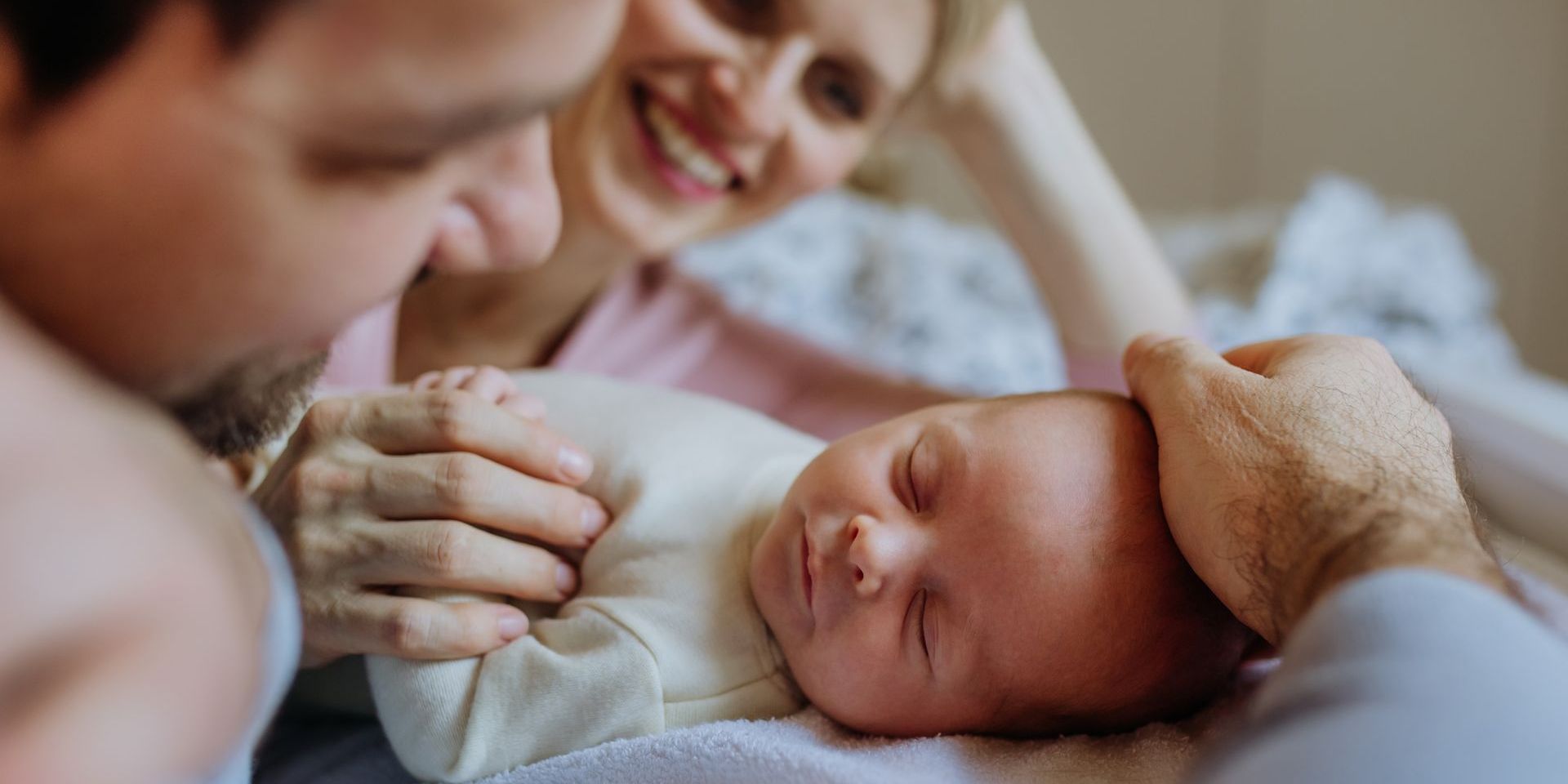 A man and woman are holding a newborn baby on a bed.