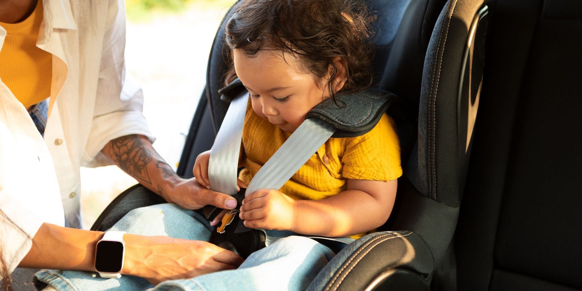 A man is putting a baby in a car seat.