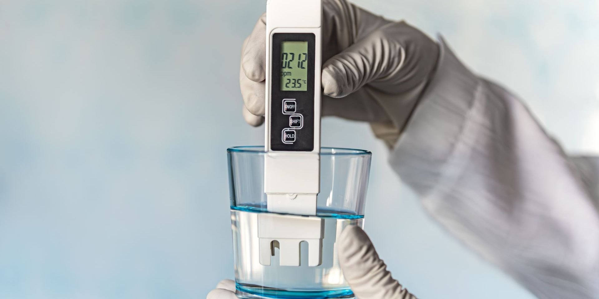 A person is measuring the ph of a glass of water.