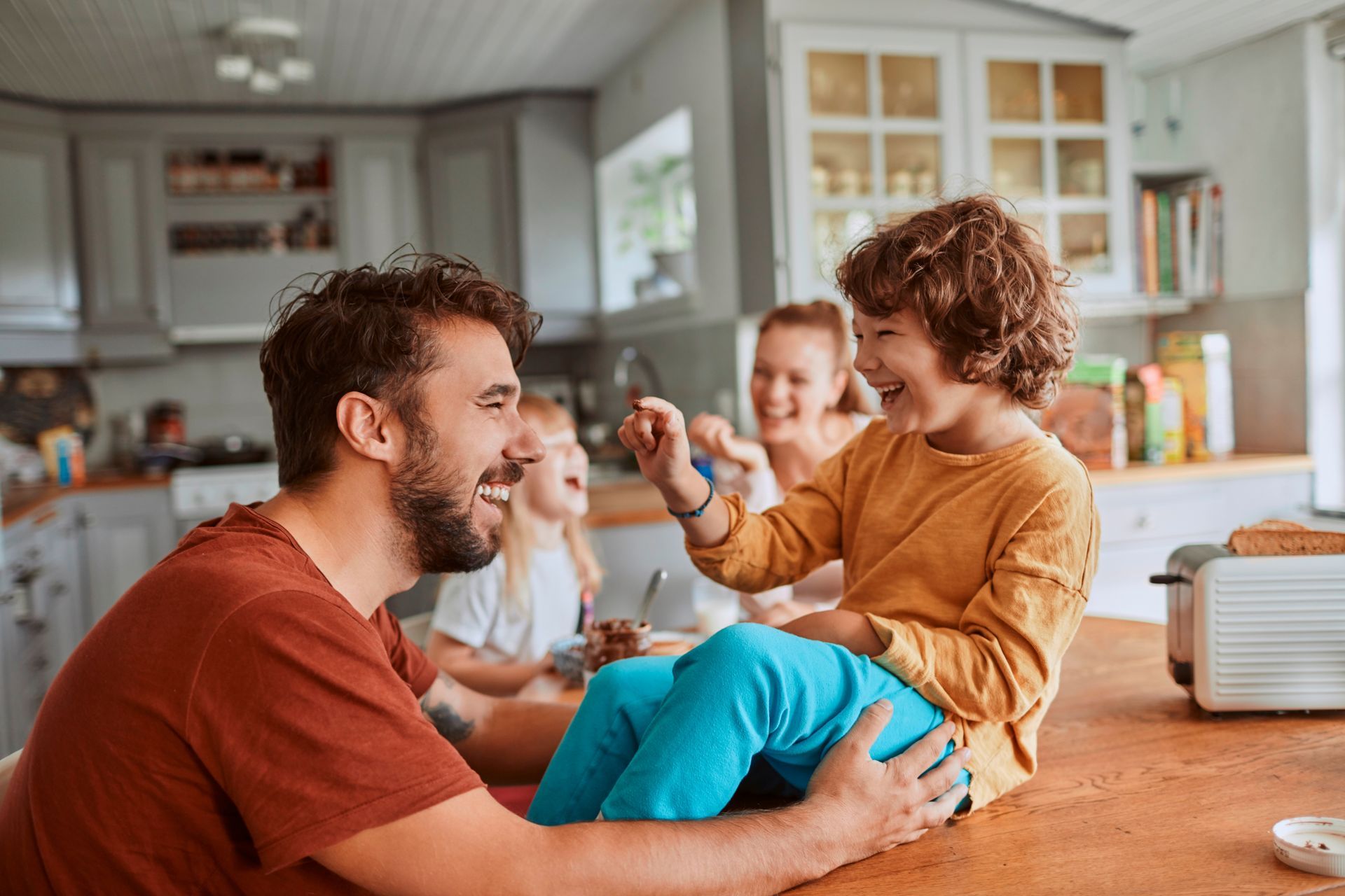 A man is holding a child on his lap in a kitchen.