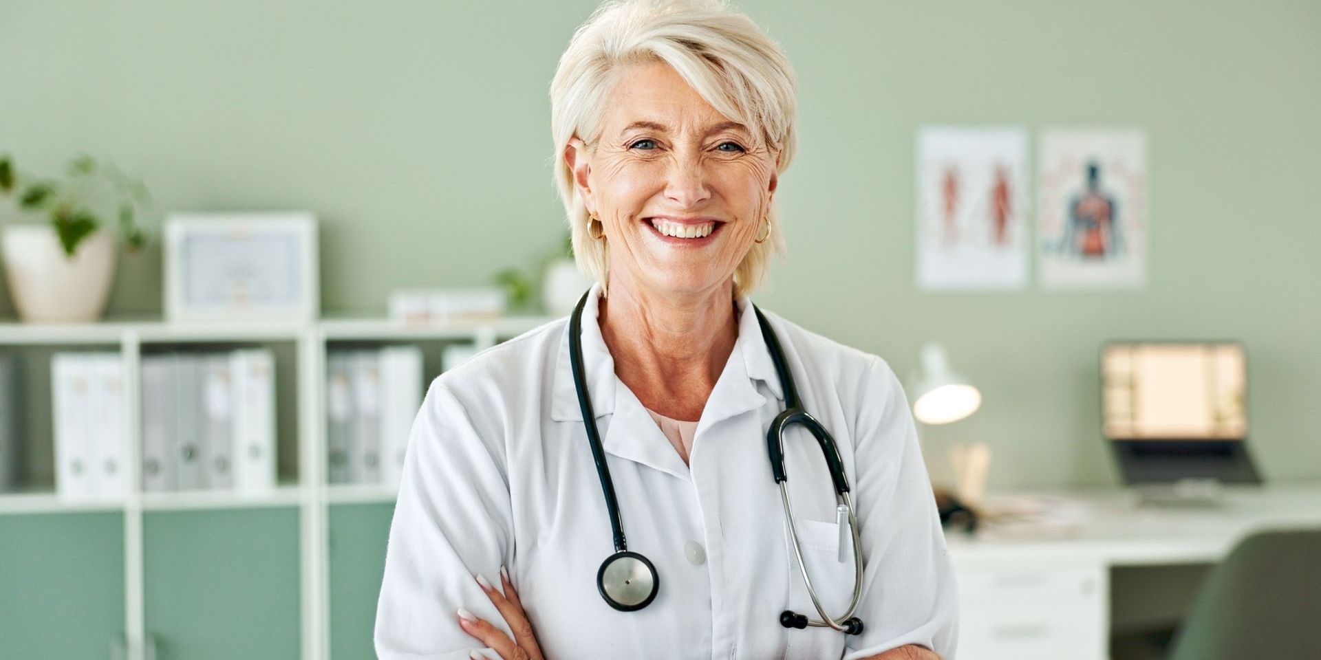 A female doctor with a stethoscope around her neck is smiling for the camera.