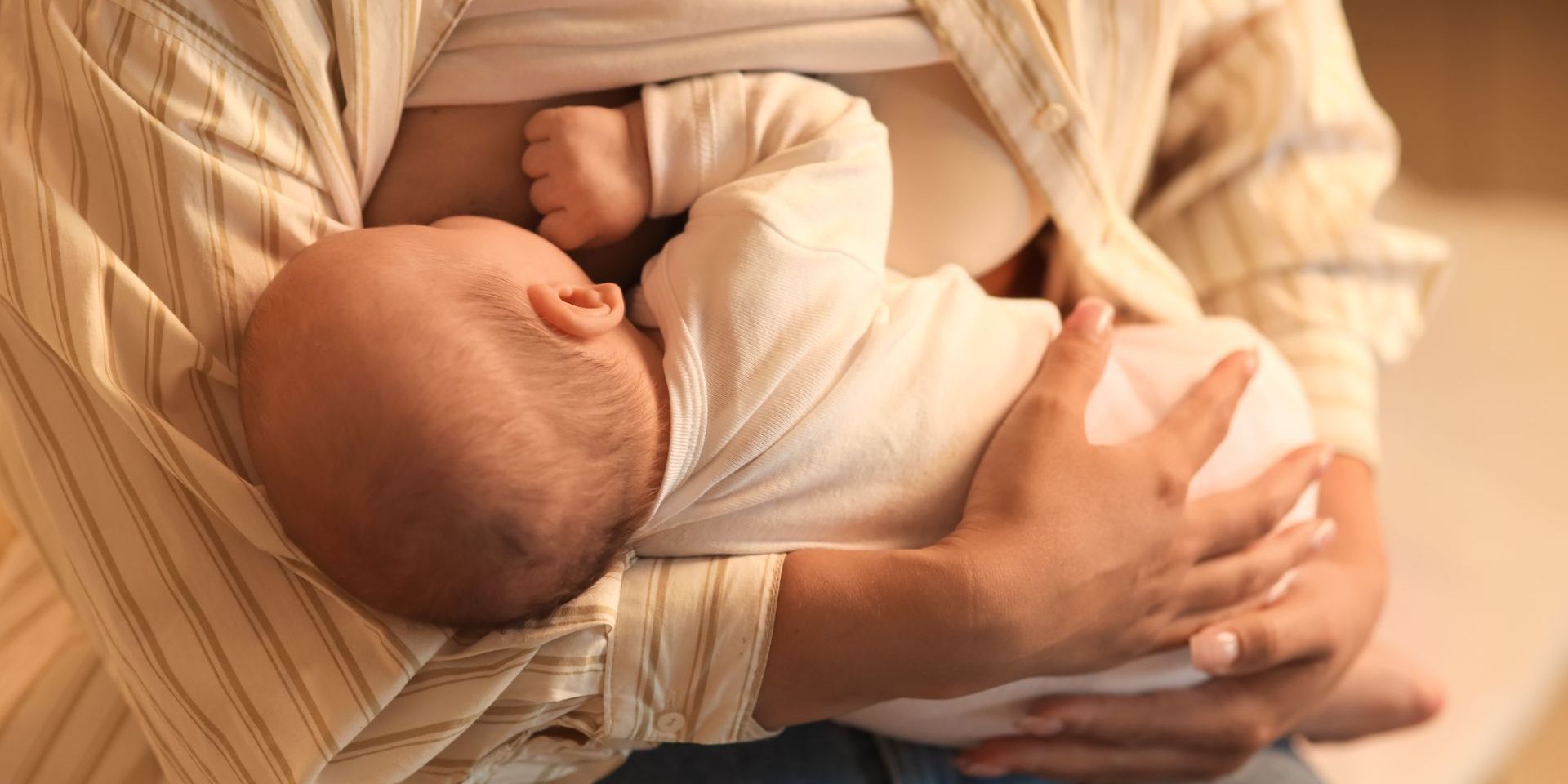 A woman is breastfeeding her baby in her arms.