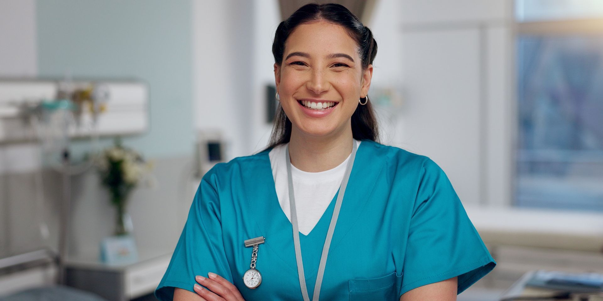 A nurse is smiling for the camera in a hospital room.