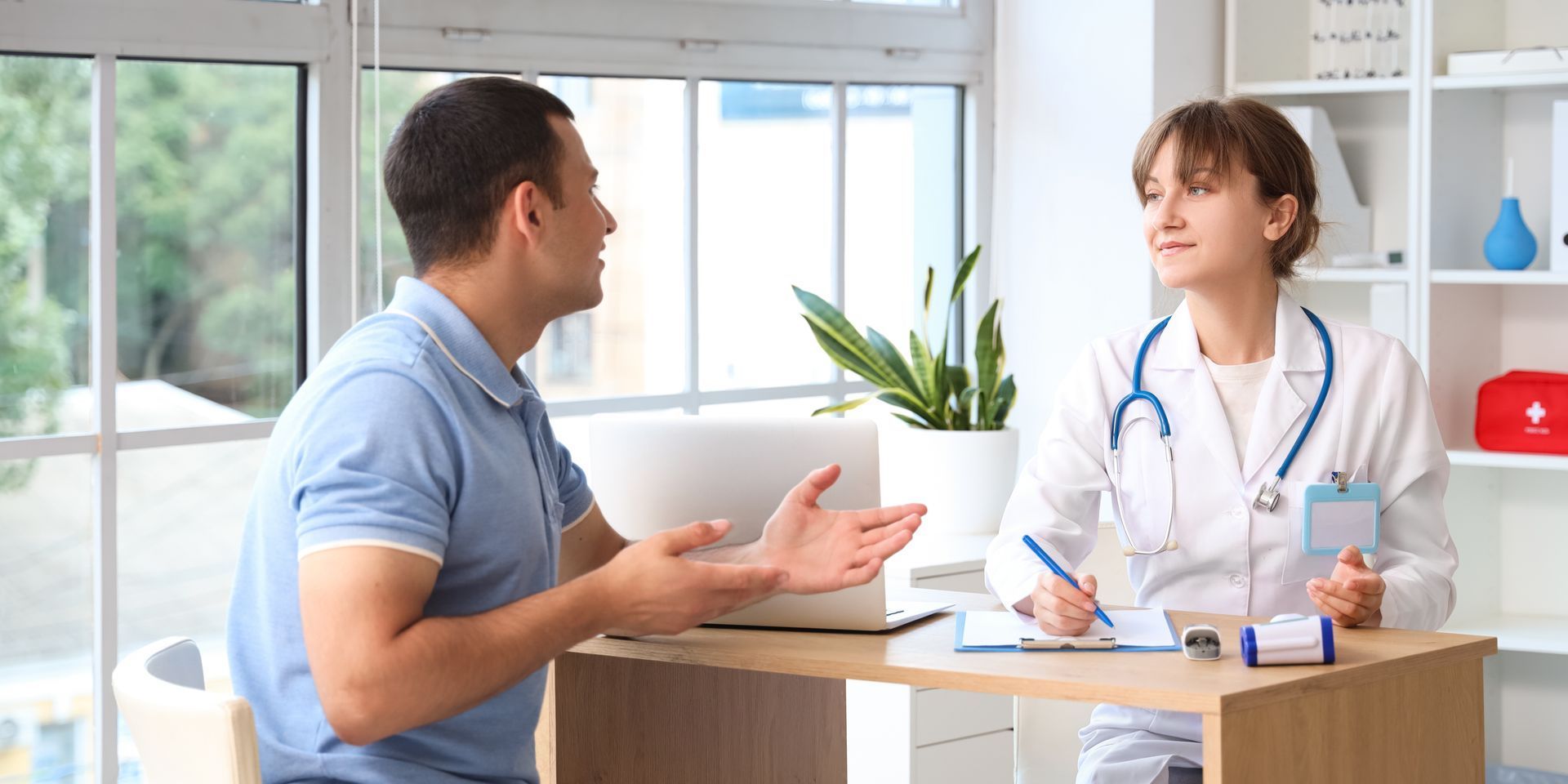 A doctor is talking to a patient at a desk in a hospital.