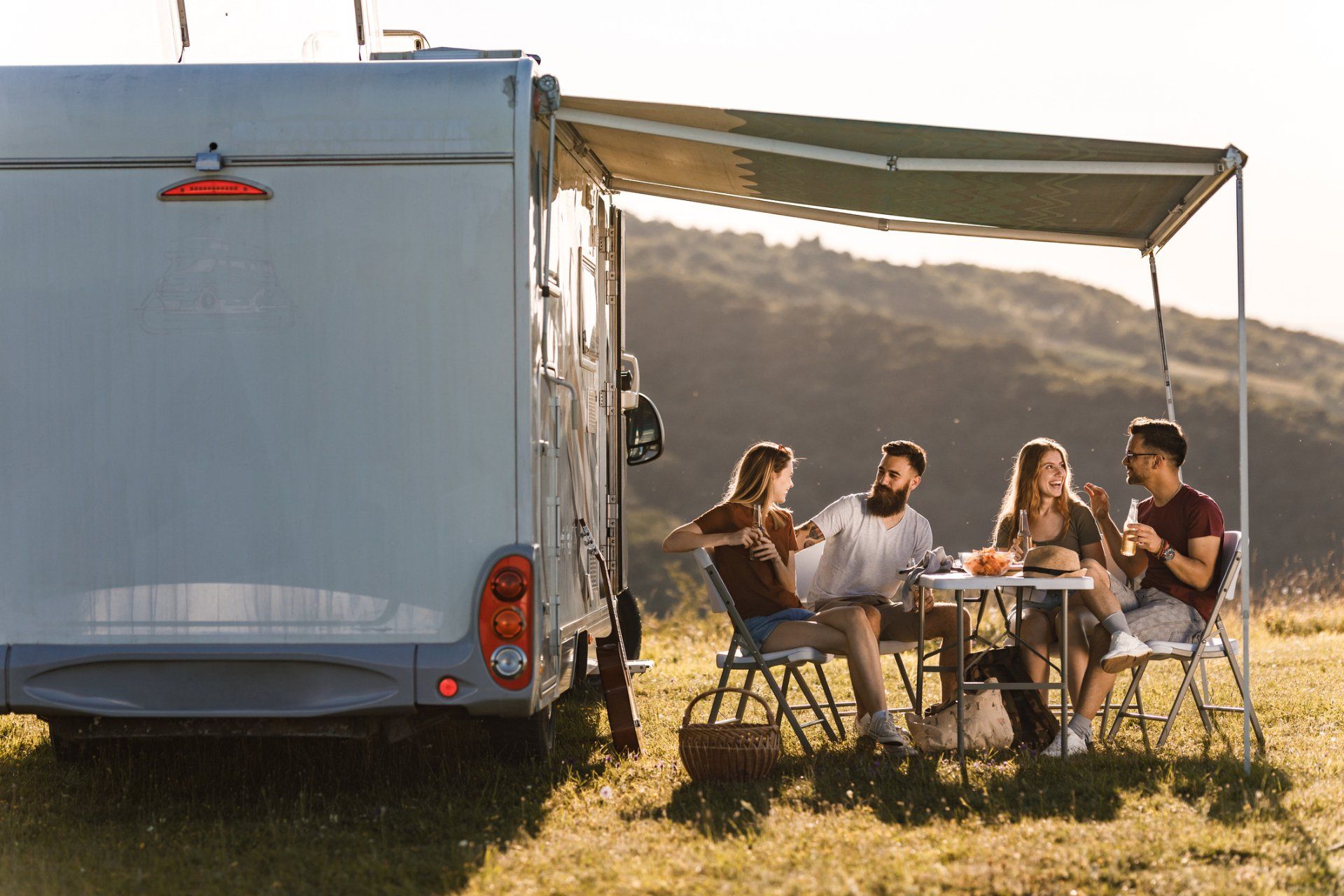 Un gruppo di persone è seduto a un tavolo davanti a un camper.