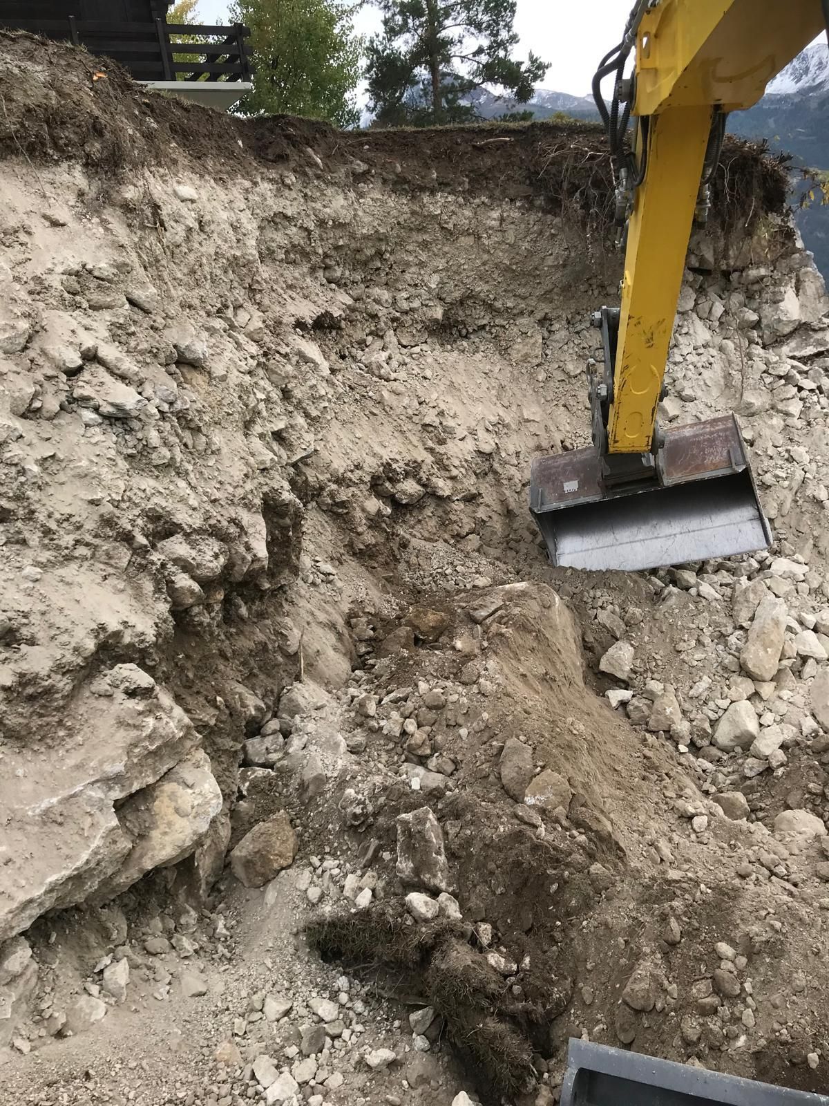 Godet d'excavatrice creusant un talus de terre sur un chantier de construction