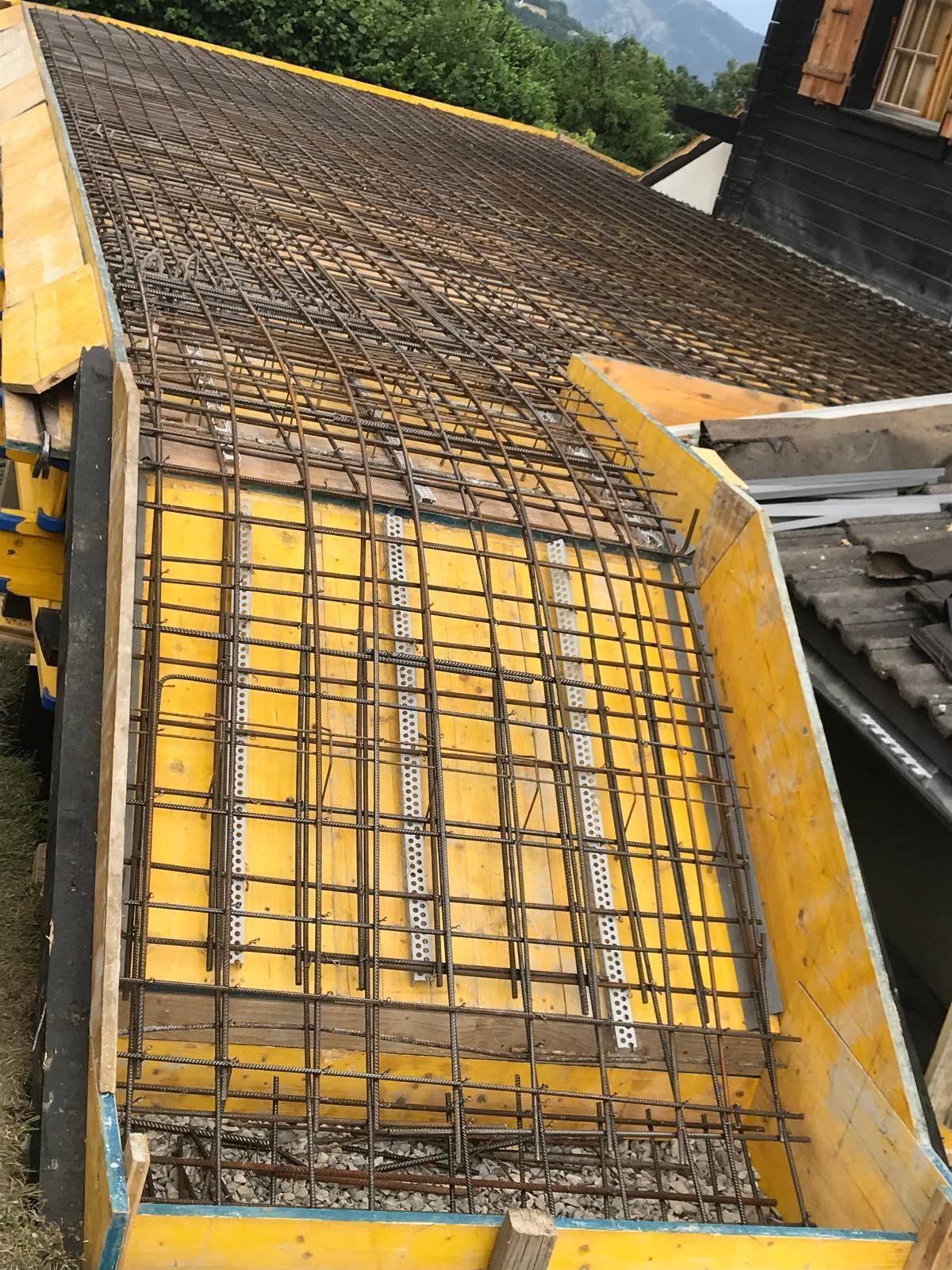 Coffrage de construction jaune avec armature en acier sur un toit, vu de biais.