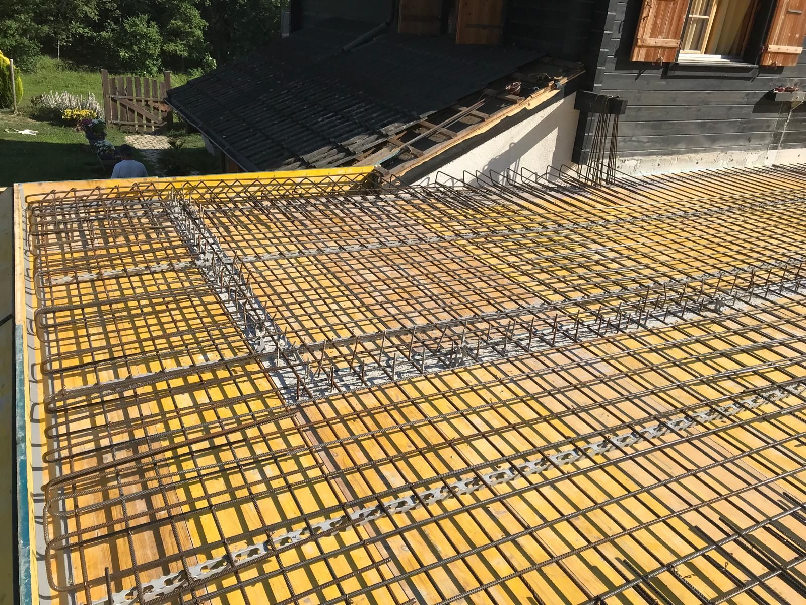 Membrane d'étanchéité jaune recouverte d'armatures en acier sur un toit en pente en construction