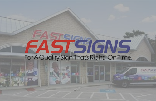 The front of a fast signs store with two vans parked in front of it.