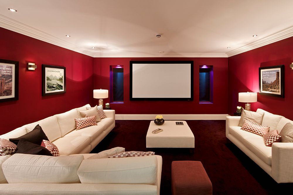 A living room with red walls and a projector screen