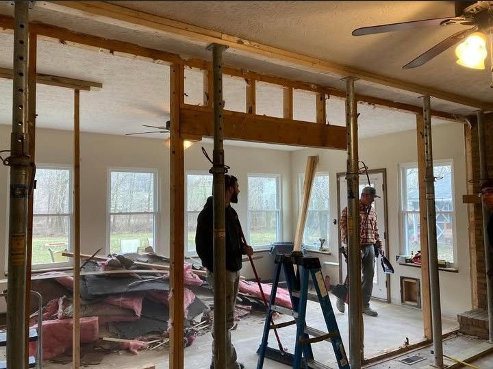 A man is standing on a ladder in a room under construction.
