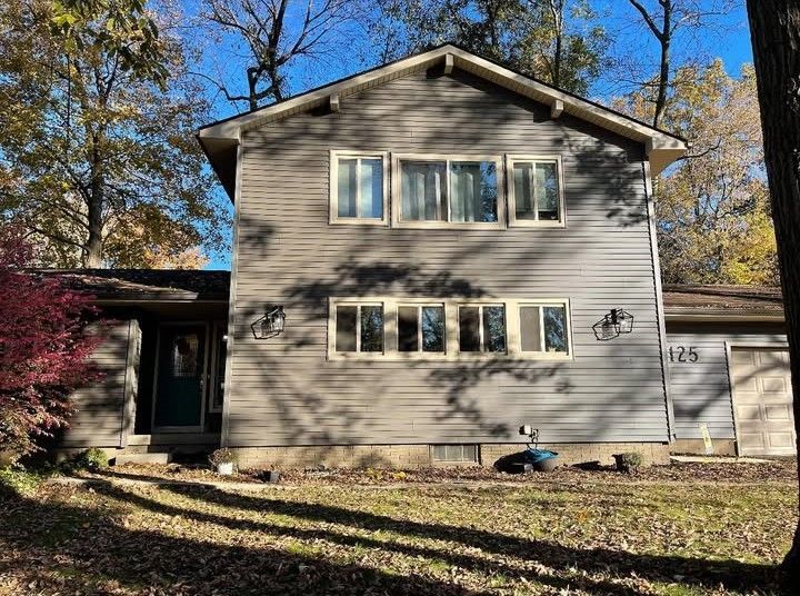 A large house with a lot of windows is surrounded by trees on a sunny day.