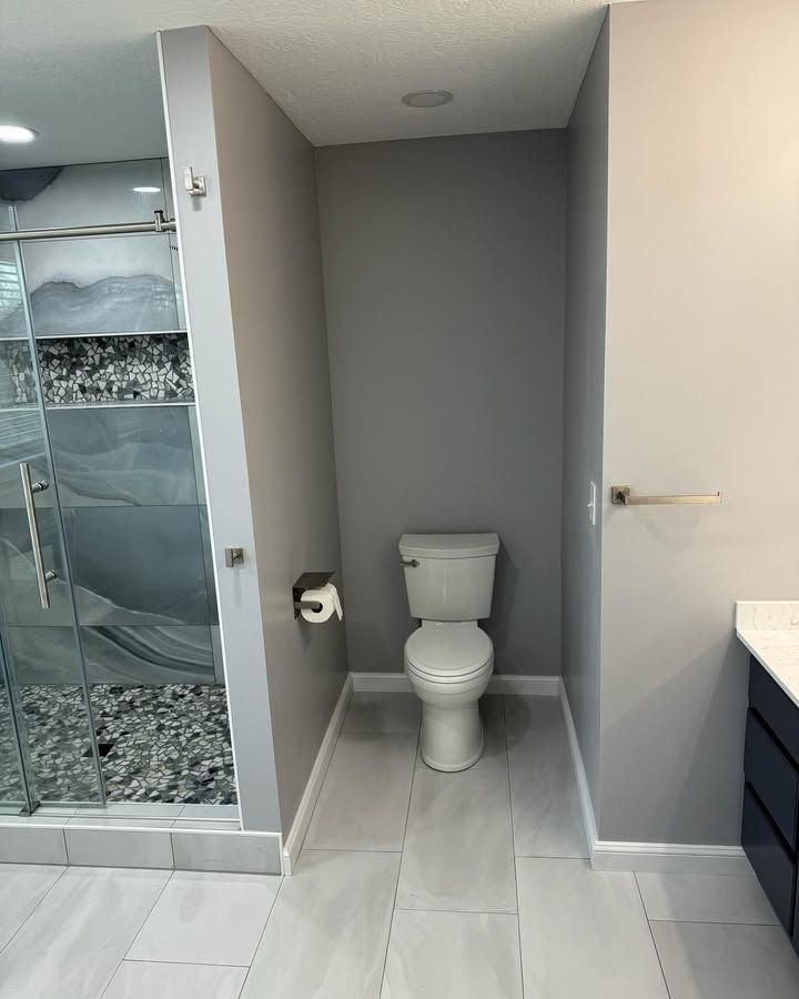 A bathroom with a toilet , sink and shower.