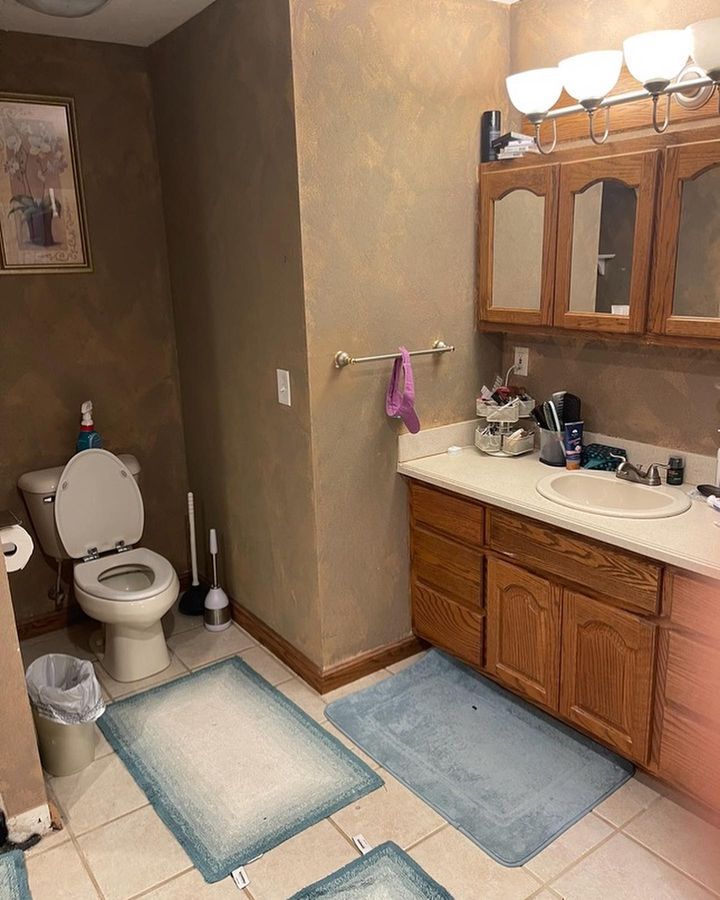 A bathroom with a toilet , sink , and cabinets.