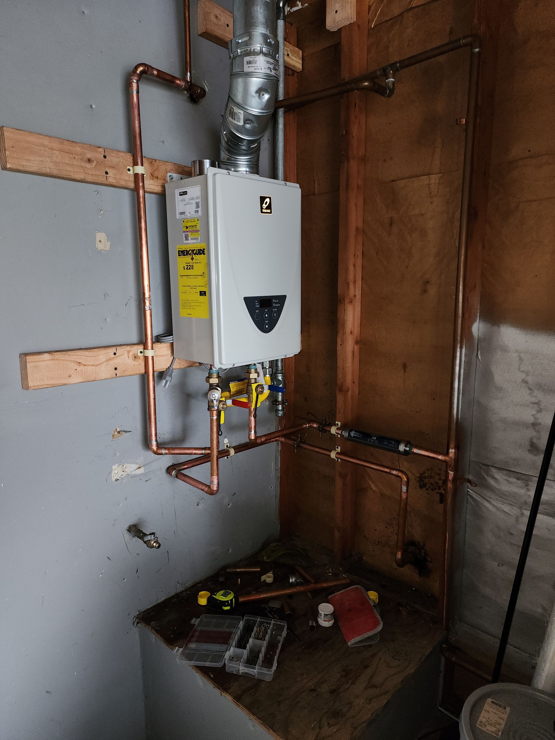 A water heater is being installed in a room with copper pipes.