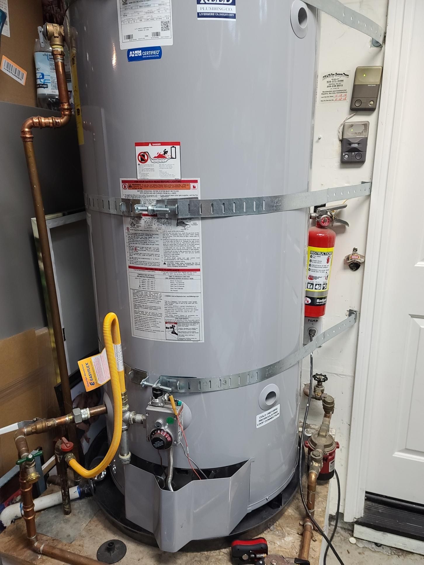 A water heater is sitting in a room next to a door.