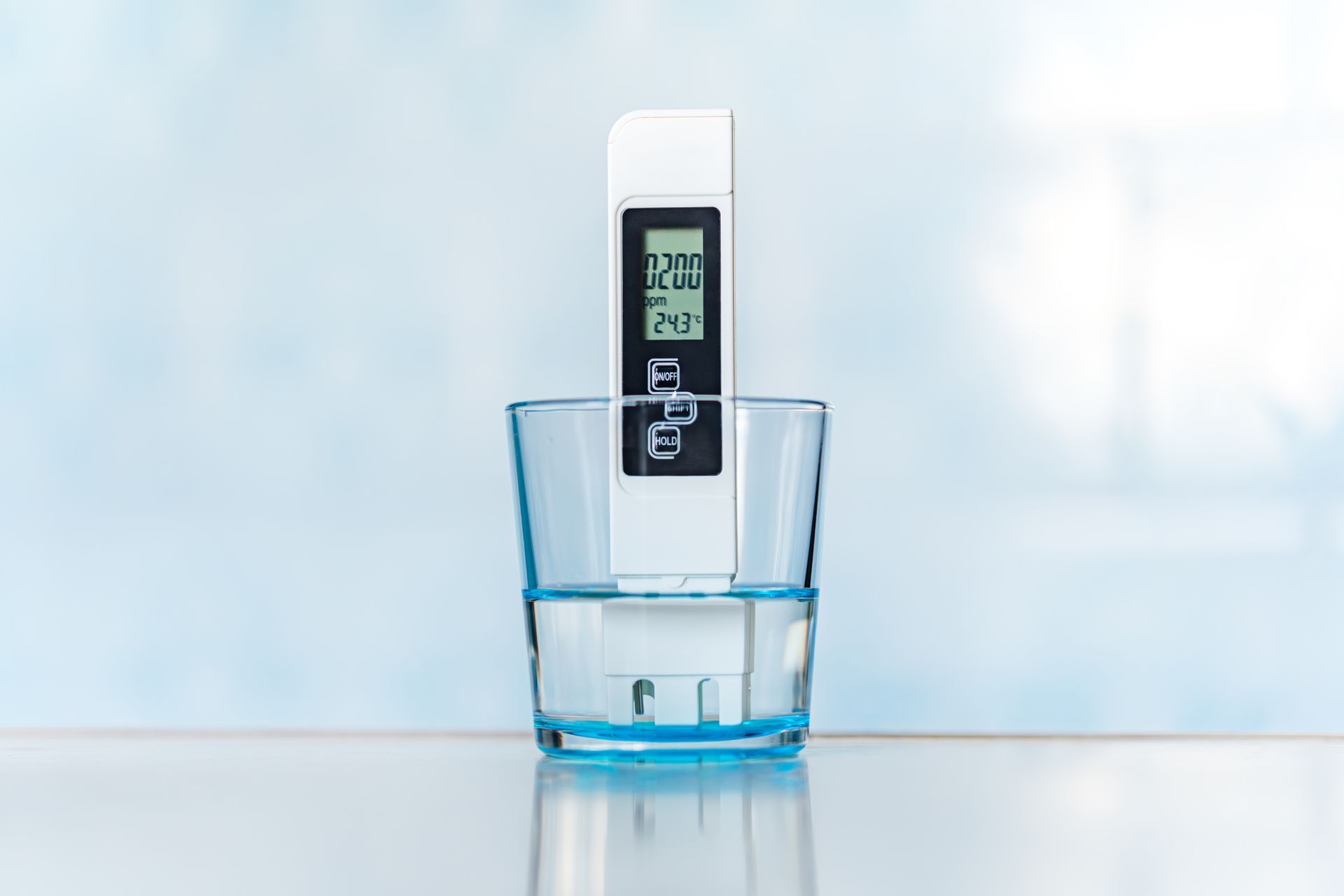 A digital thermometer is sitting in a glass of water.