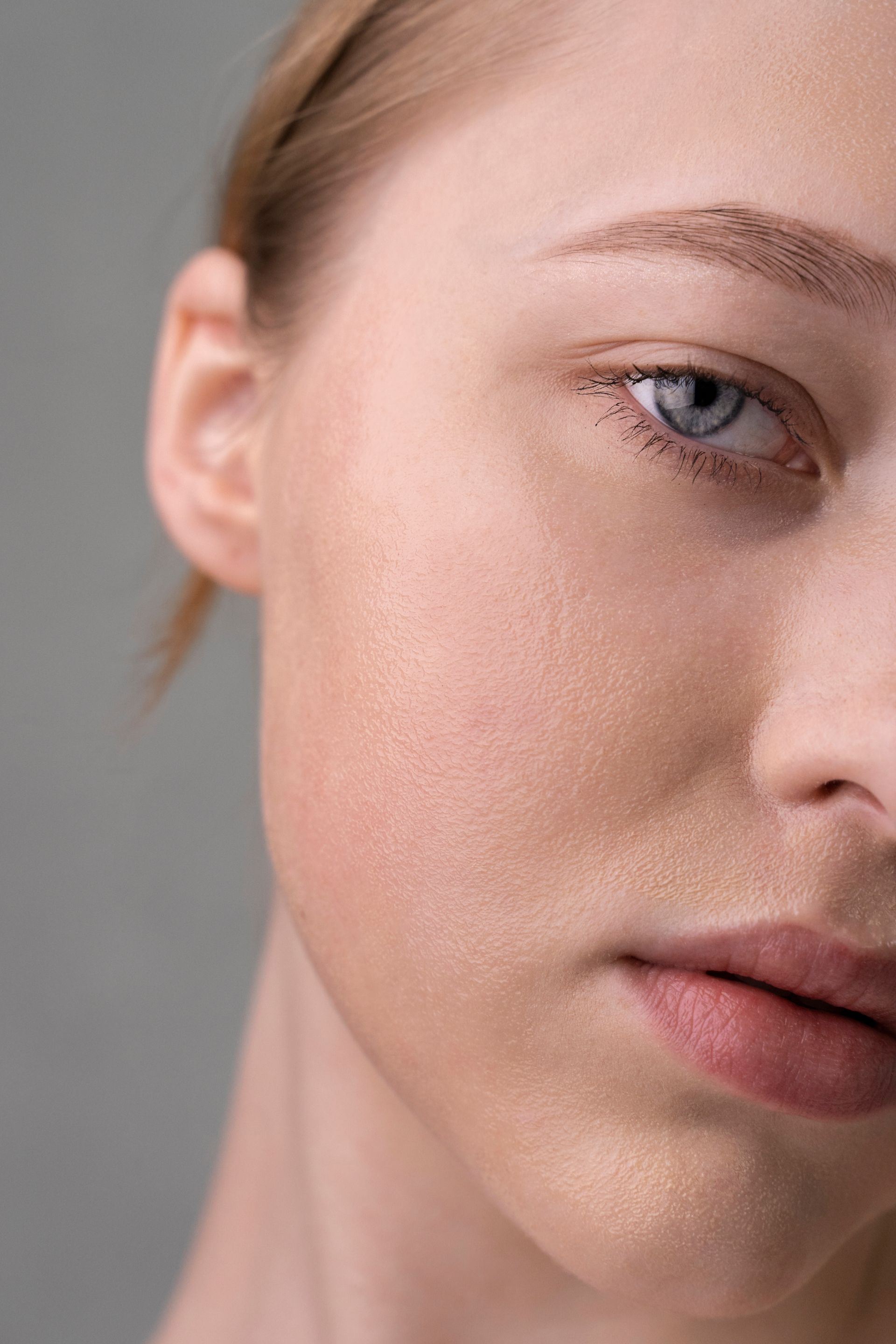 A close up of a woman 's face with a gray background.