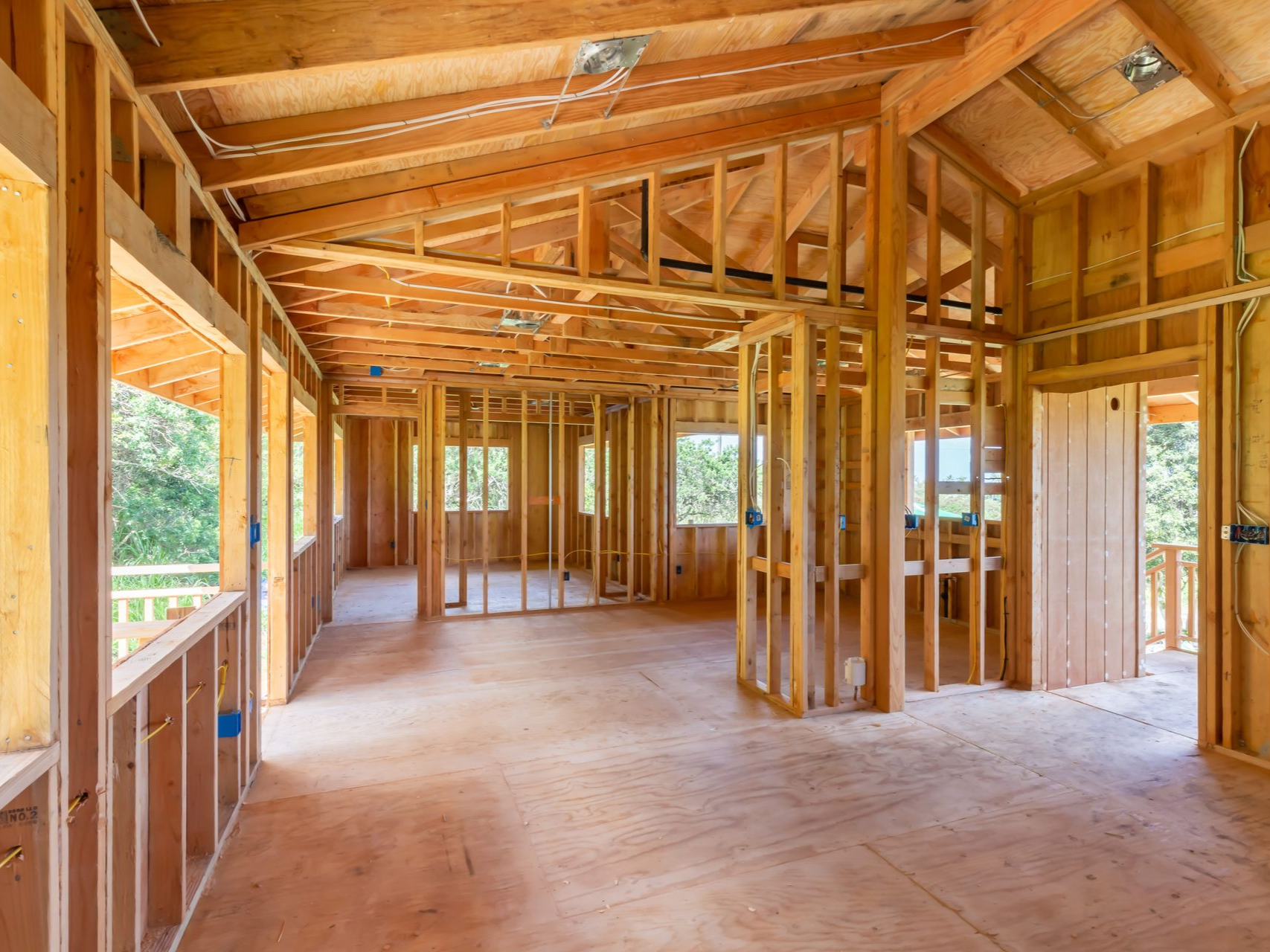 A wide shot of a room under construction, showing bare wood wall framing and subfloors with open, unfinished architecture.