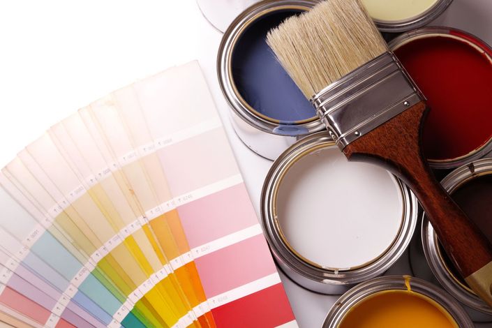 Campioni di colore e barattoli di vernice aperti con pennelli disposti su una tavolozza per la selezione dei colori.