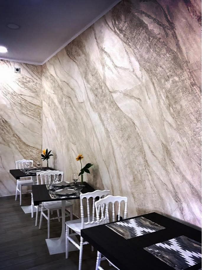 Tavolini da caffè moderni in stile classico, con motivi in bianco e nero, accanto a una grande parete con rivestimento effetto marmo.