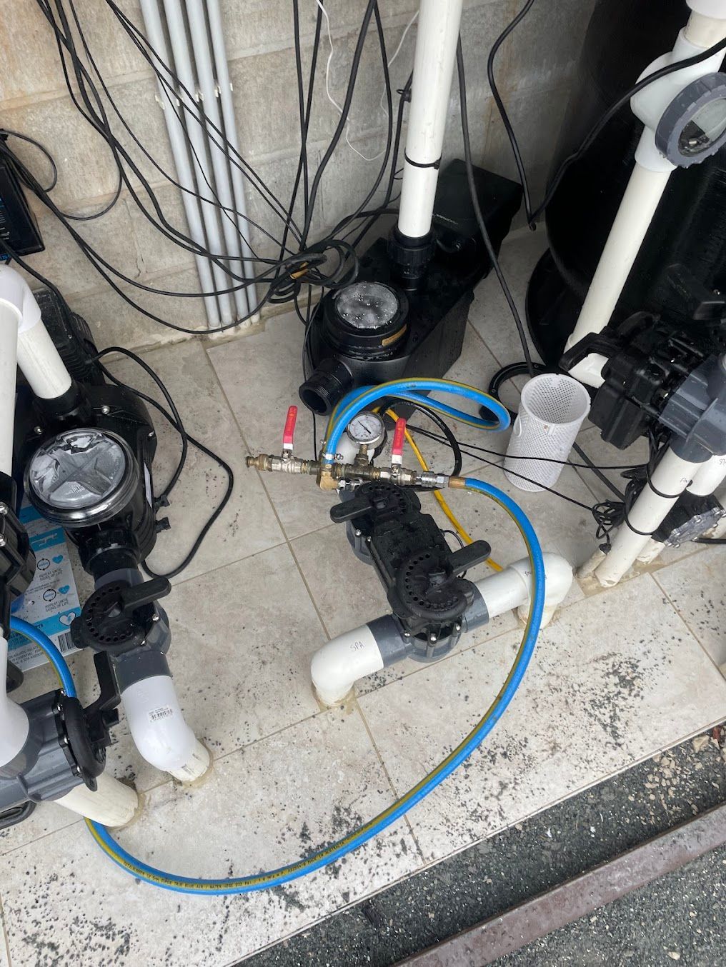 Plumbing System With Pumps, Pipes, and Gauges. Blue Hose Connects Components on a Tiled Surface — Leak N Pool In Southport, QLD