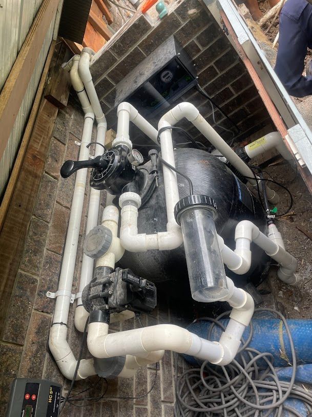 Pool Pump System With Black Filter, White Pipes, and Brick Wall — Leak N Pool In Southport, QLD
