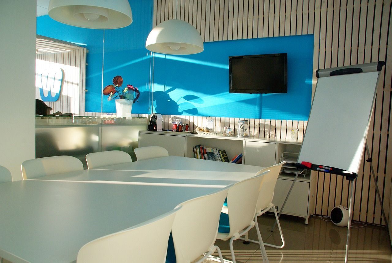 An office space with a conference table, chairs, and a blue wall.