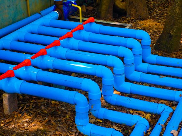 A bunch of blue pipes are laying on the ground.