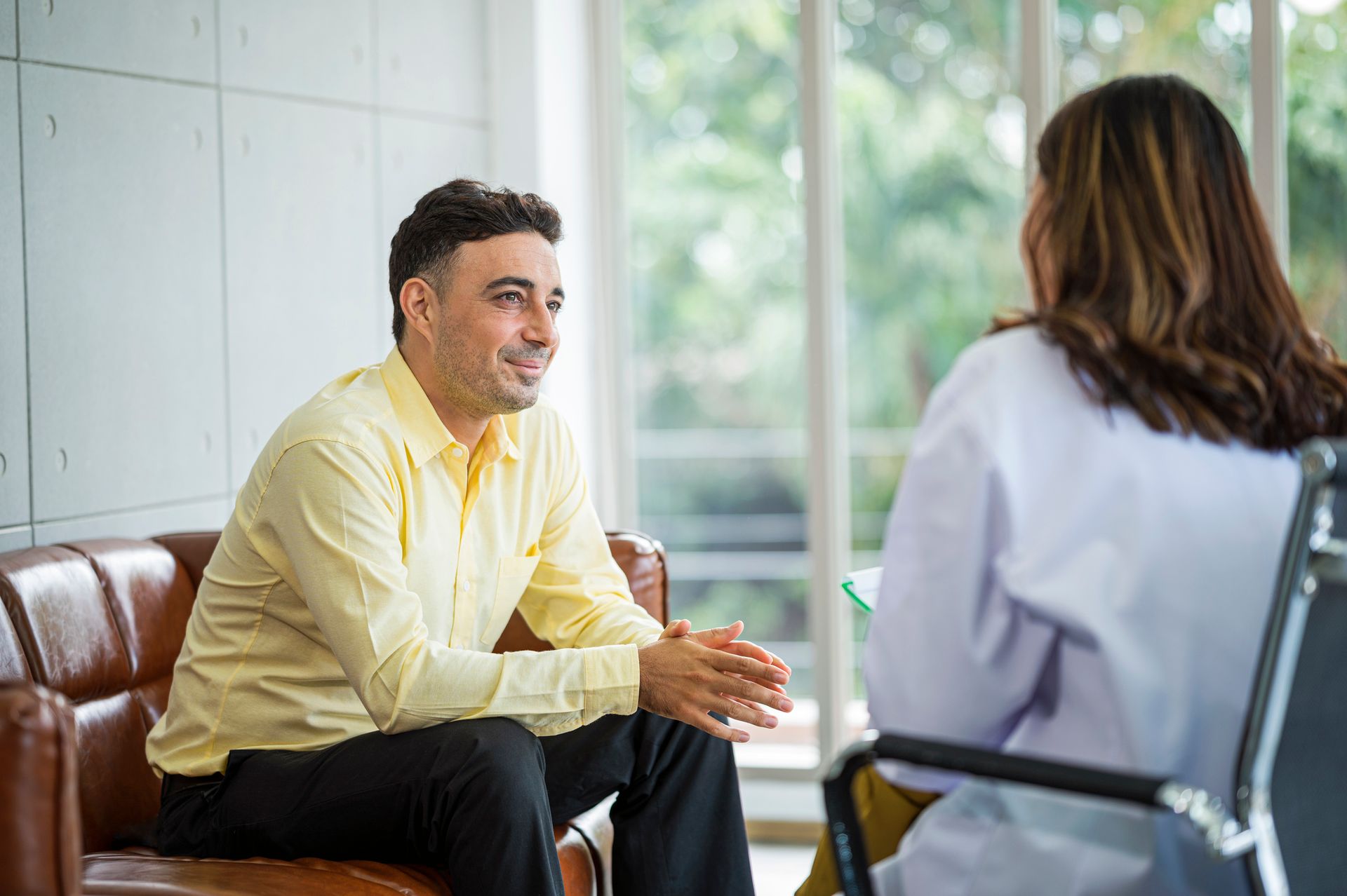 A man is sitting on a couch talking to a woman.