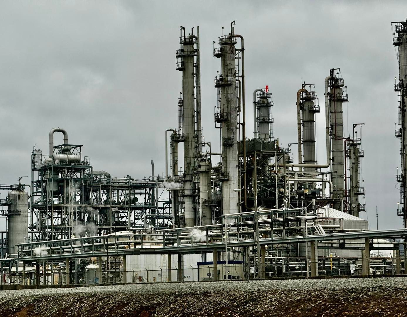Industrial oil refinery under a cloudy sky. Complex structures of pipes and towers.