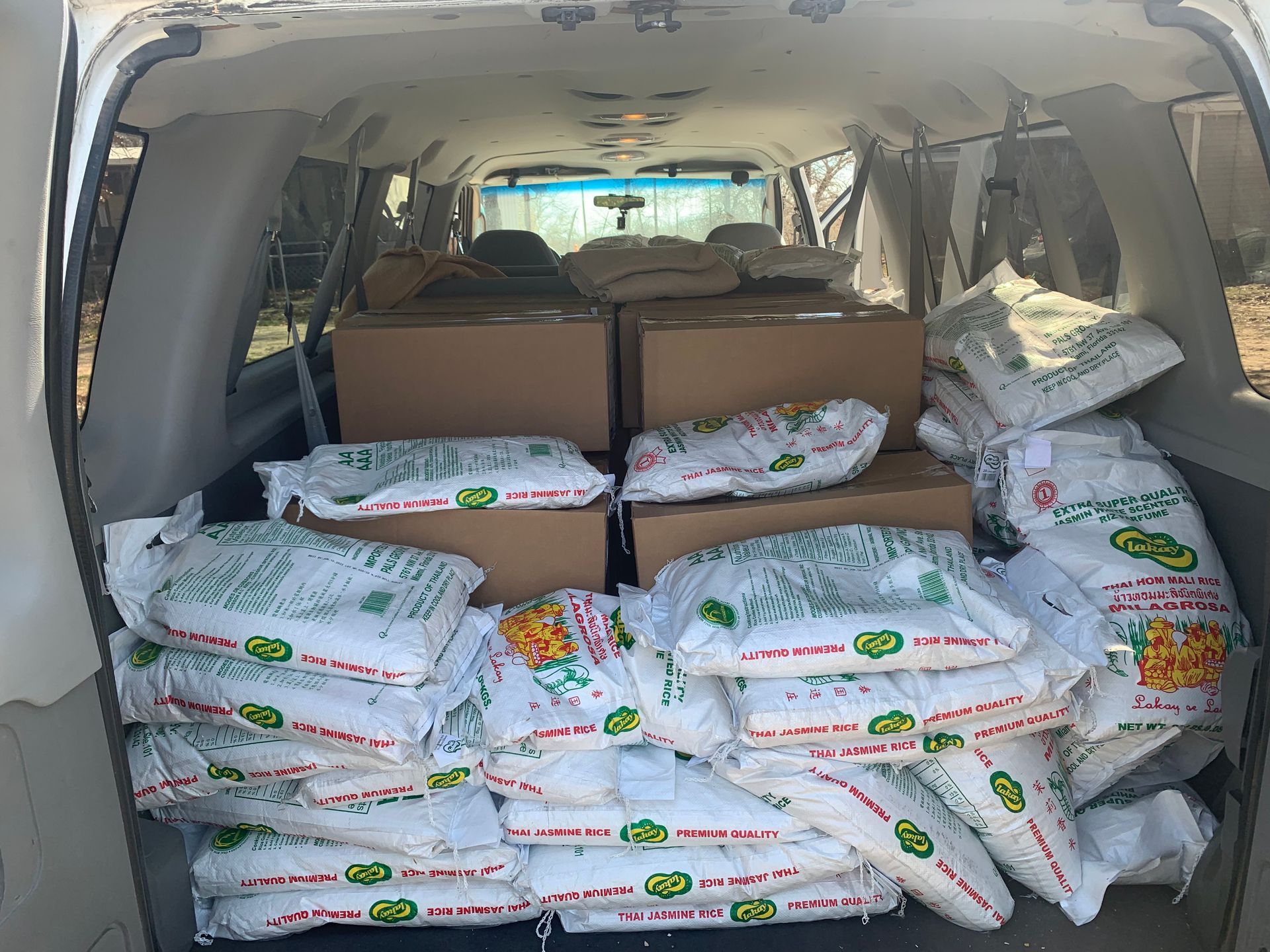 Van interior filled with numerous white bags and cardboard boxes.