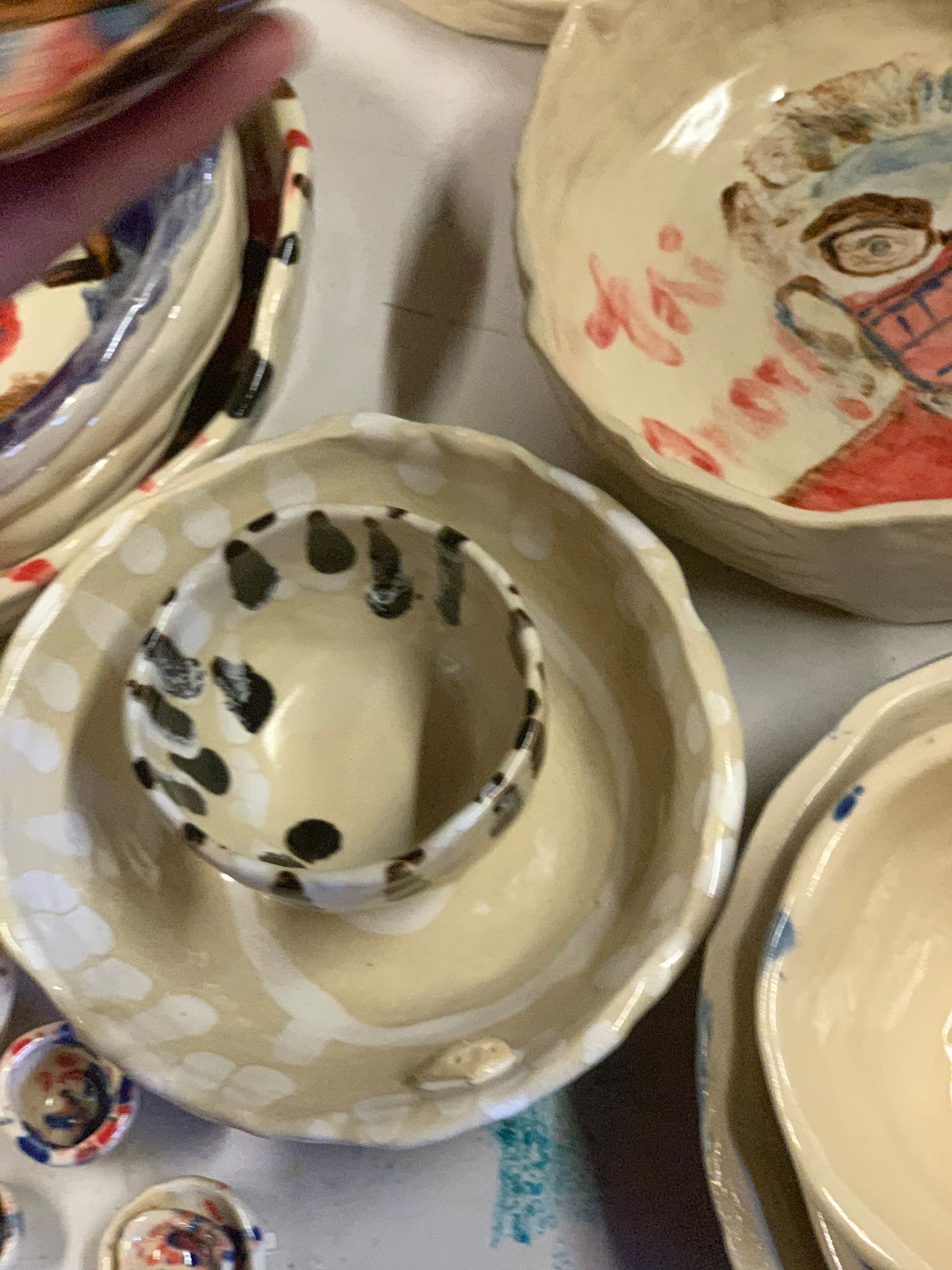 Ceramic bowls of various sizes, some with painted designs, stacked and arranged on a table.