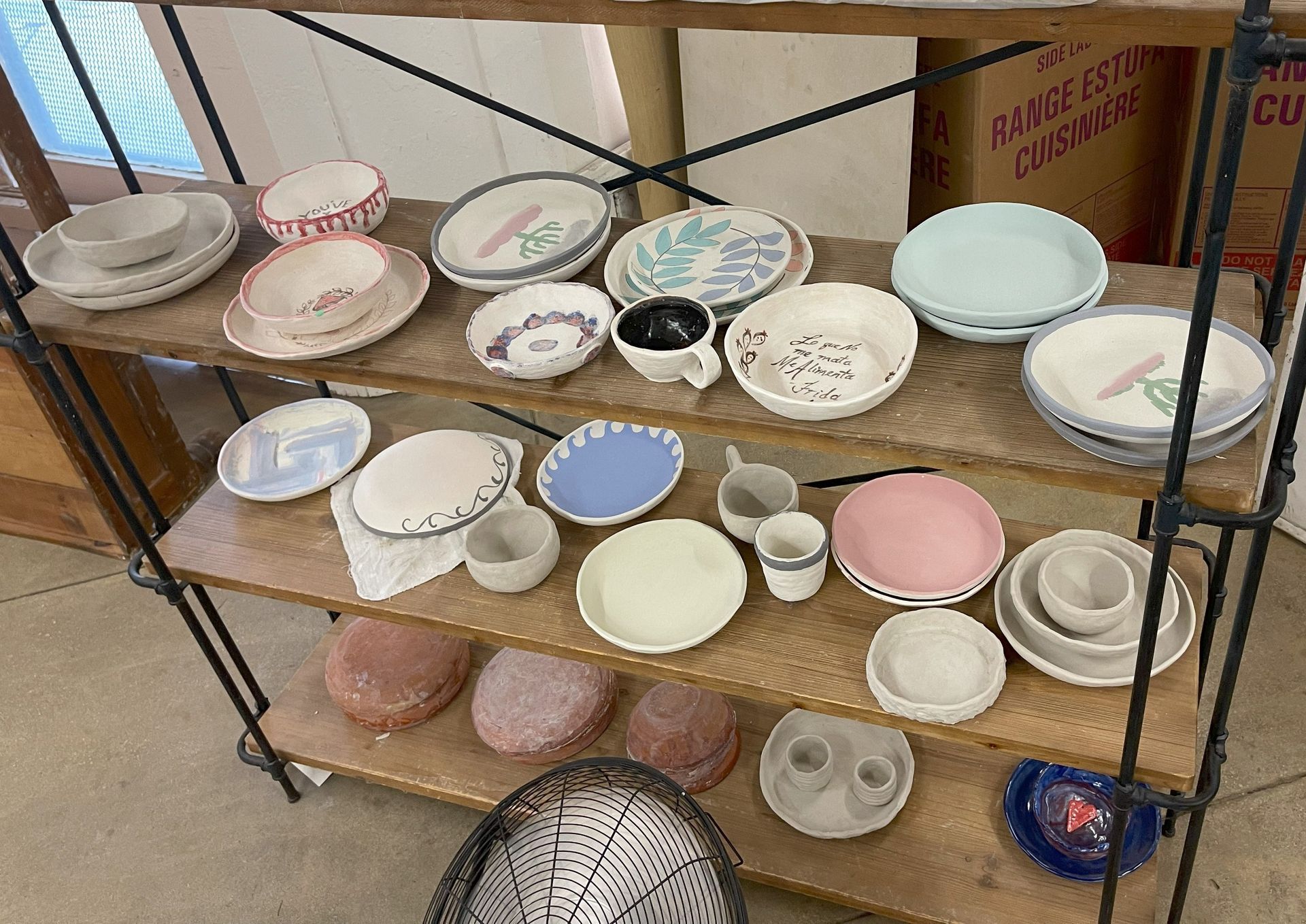 Shelves display various ceramic plates, bowls, and cups in a shop setting.