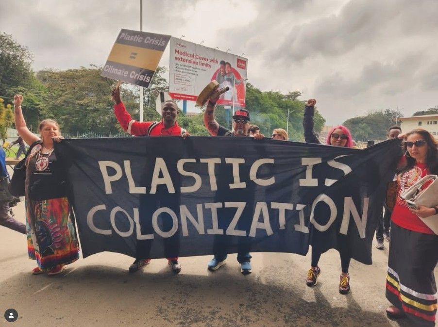Protestors march, raising fists, holding a banner reading 