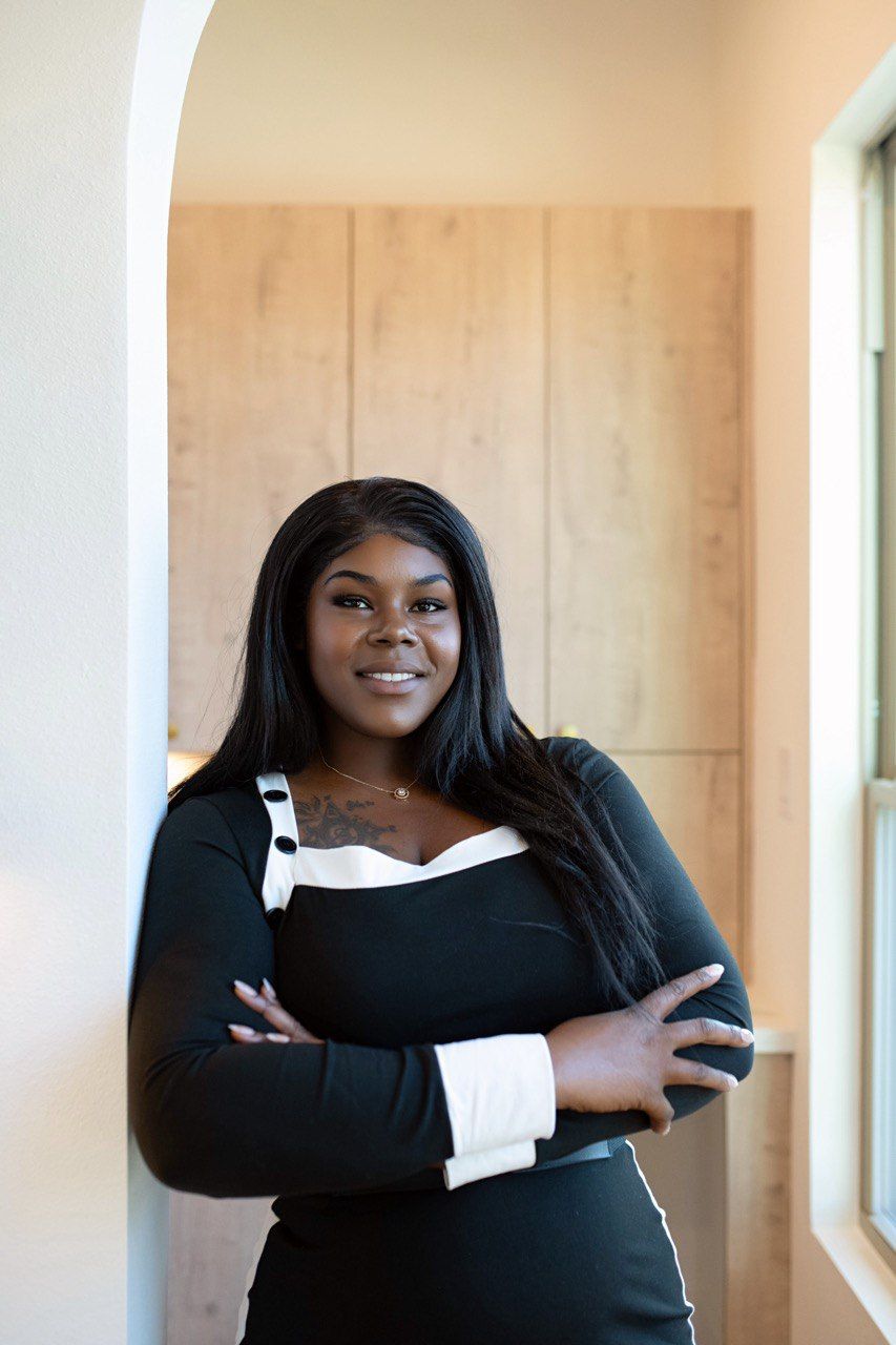 Dining room with a wooden staircase, table, chairs, and large window.