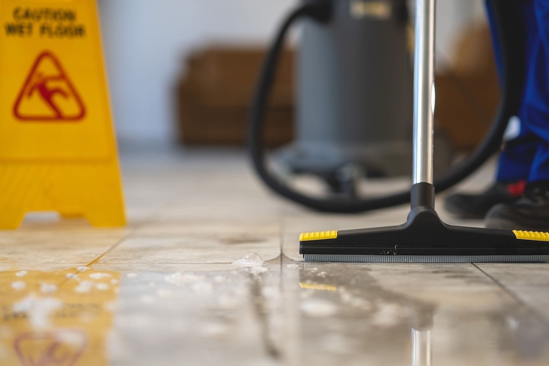 Yellow caution sign and mop cleaning a wet floor indoors