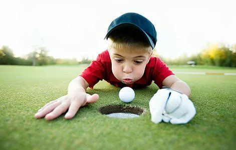 kid blowing in the golf ball