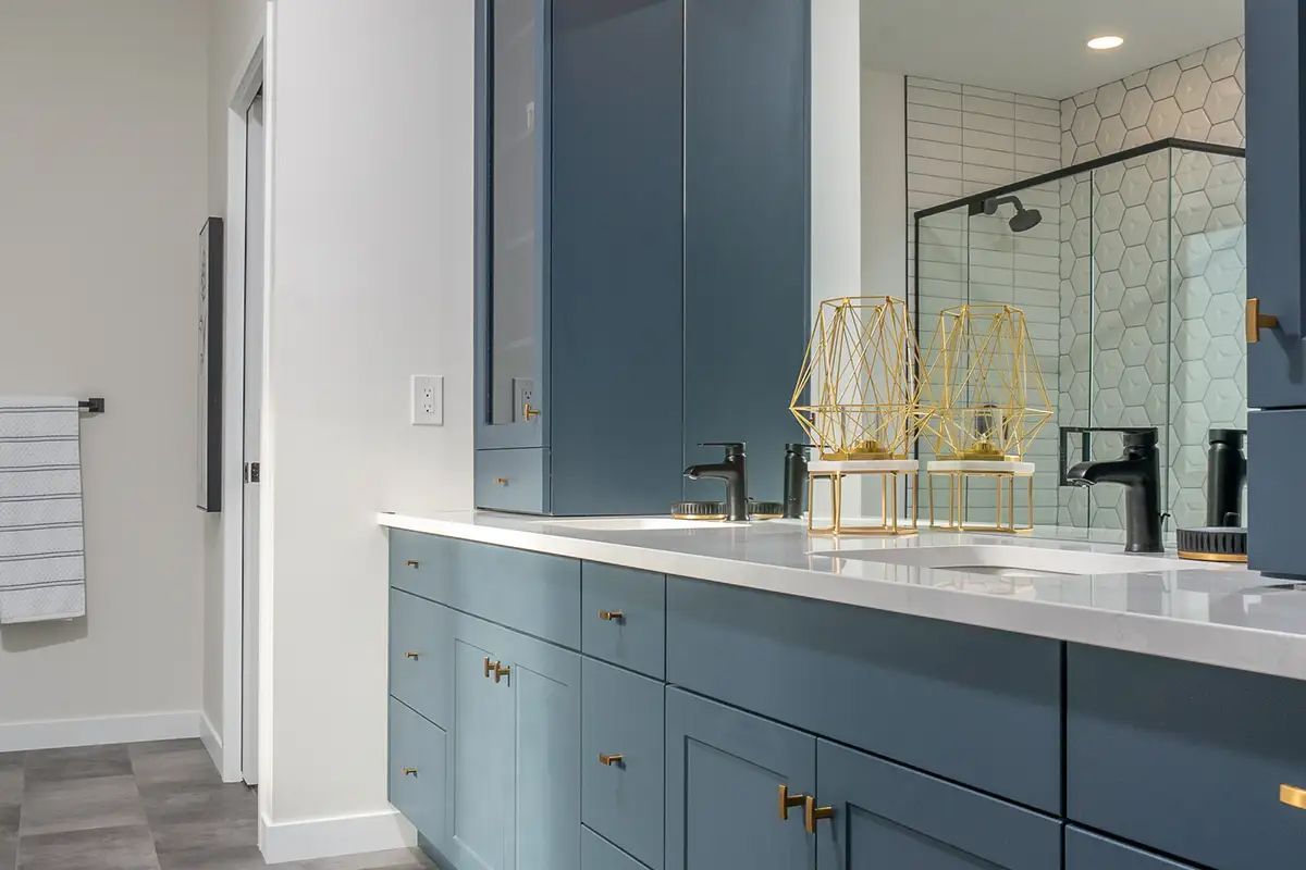 A bathroom with two sinks , a mirror and a walk in shower.