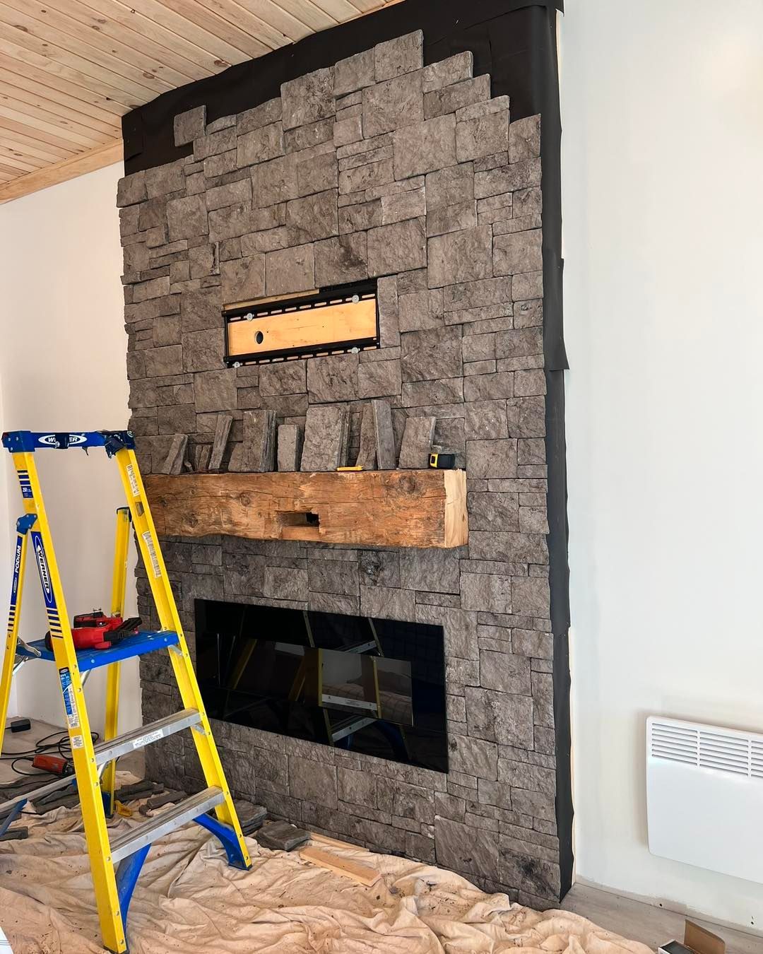 A ladder is sitting next to a fireplace in a living room.
